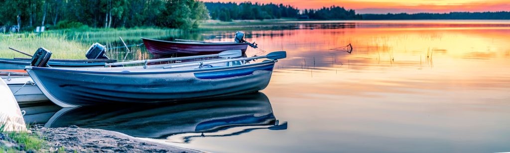 Illustration photo - summer time in Finland. Boat afloat on the Finnish lake, near to the forest