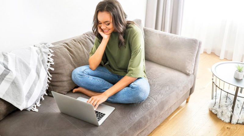Dekorativt foto av en person som arbetar på sin bärbara dator medan han sitter på en soffa.