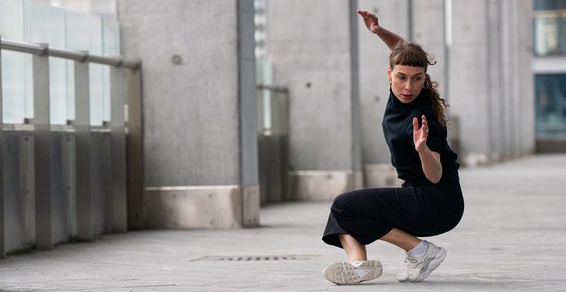 Dekorativ bild av kvinna som utövar modern dans på en stadsplats.