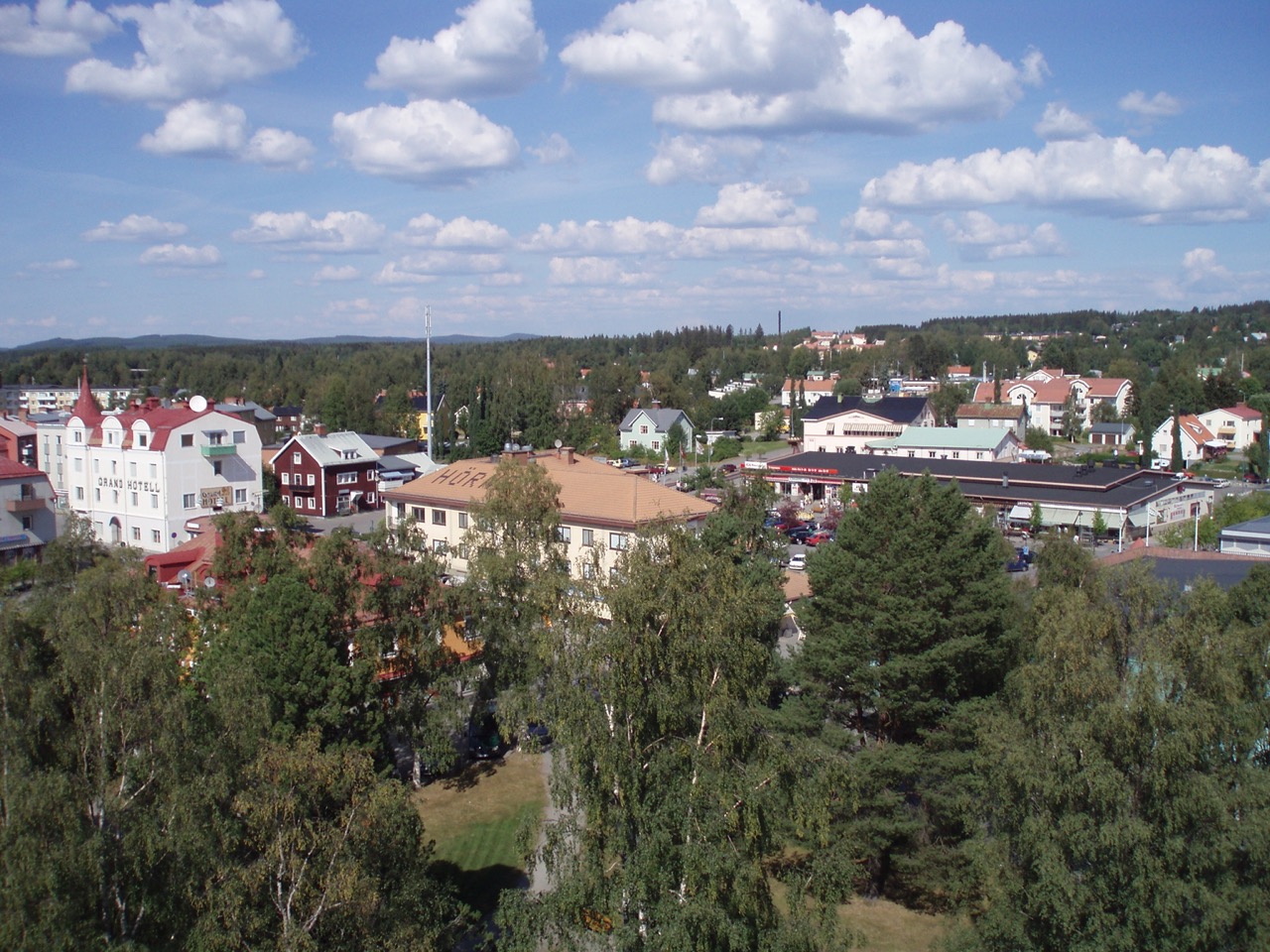 Dekorativ bild av småstad med färgglada byggnader och grönska, sett från ovan.
