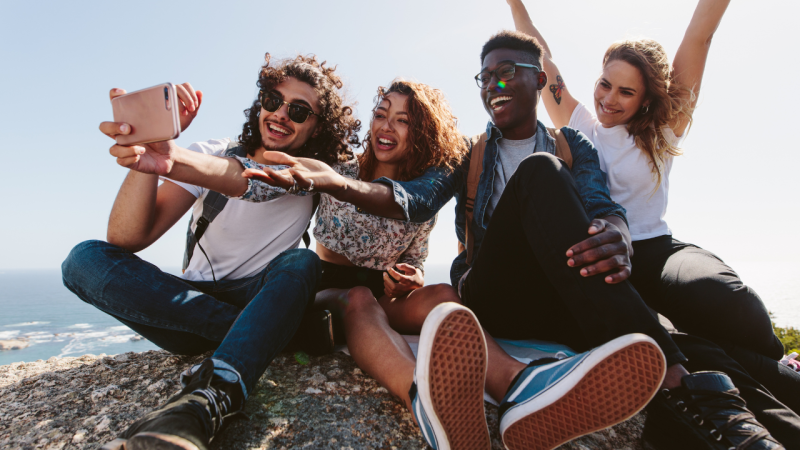 Grupp av fyra unga personer tar en selfie med sina telefoner. (Dekorativ bild)