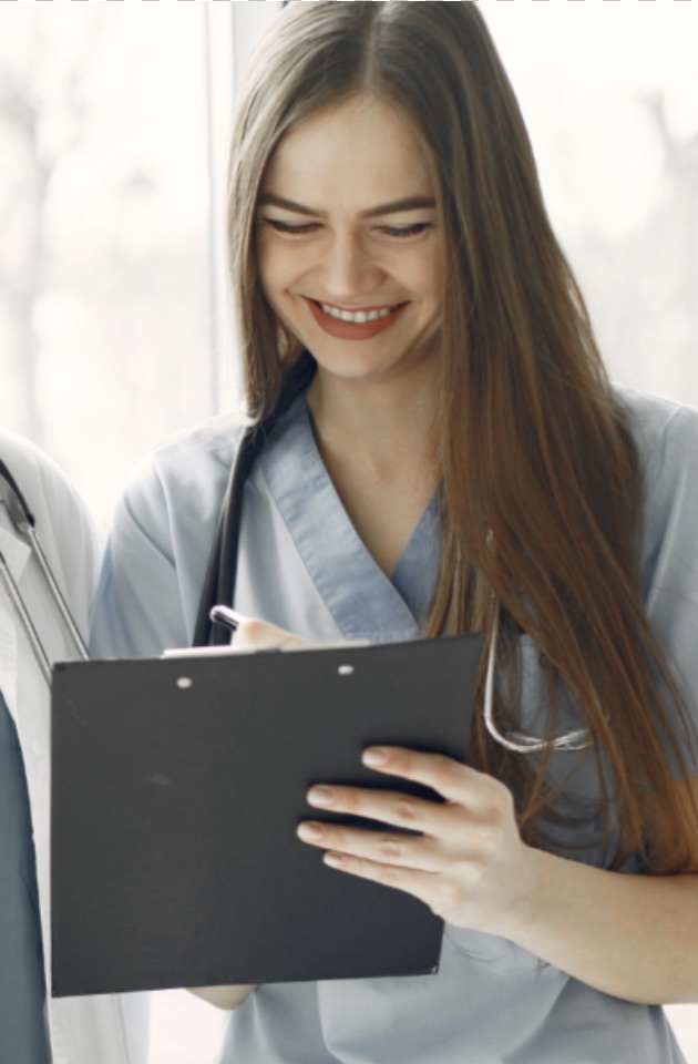 sjuksköterska med stetoskop skriver på en präm. Hon ler och har brunt långt hår samt blå sjukhuskläder