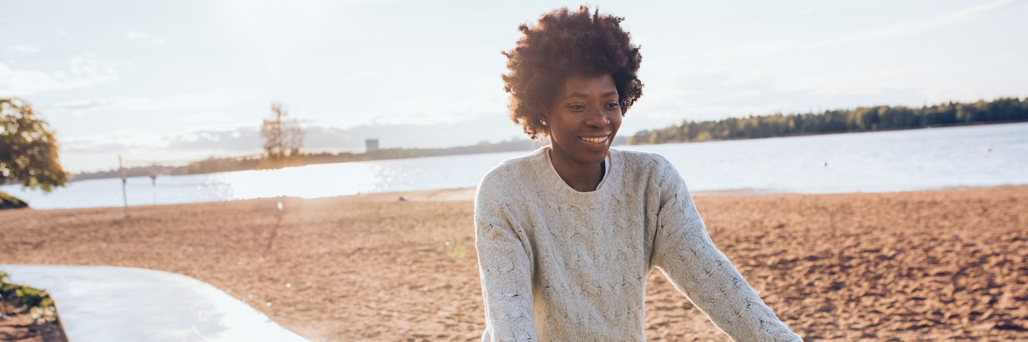 A woman with afro hair walks on the beach.