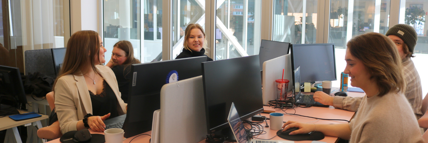 En grupp människor är sysselsatta med arbete vid datorer på ett kontor.