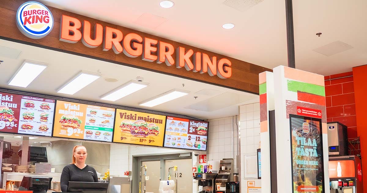 Dekorativ bild av en Burger King-restaurang med menyskyltar och anställd vid kassan.