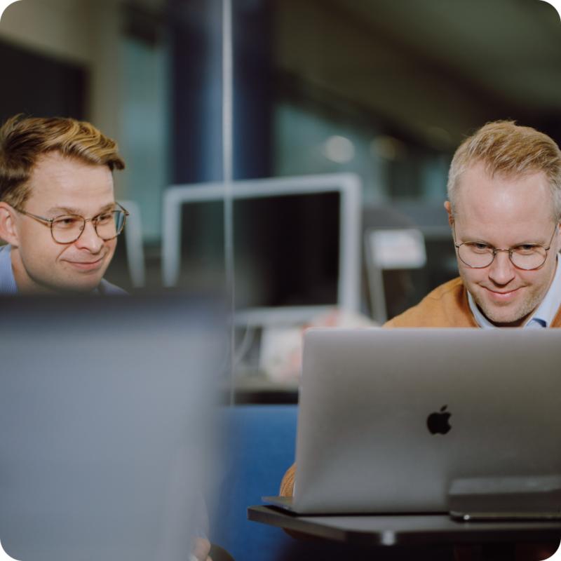 Dekorativ bild som föreställer två kollegor framför en laptop