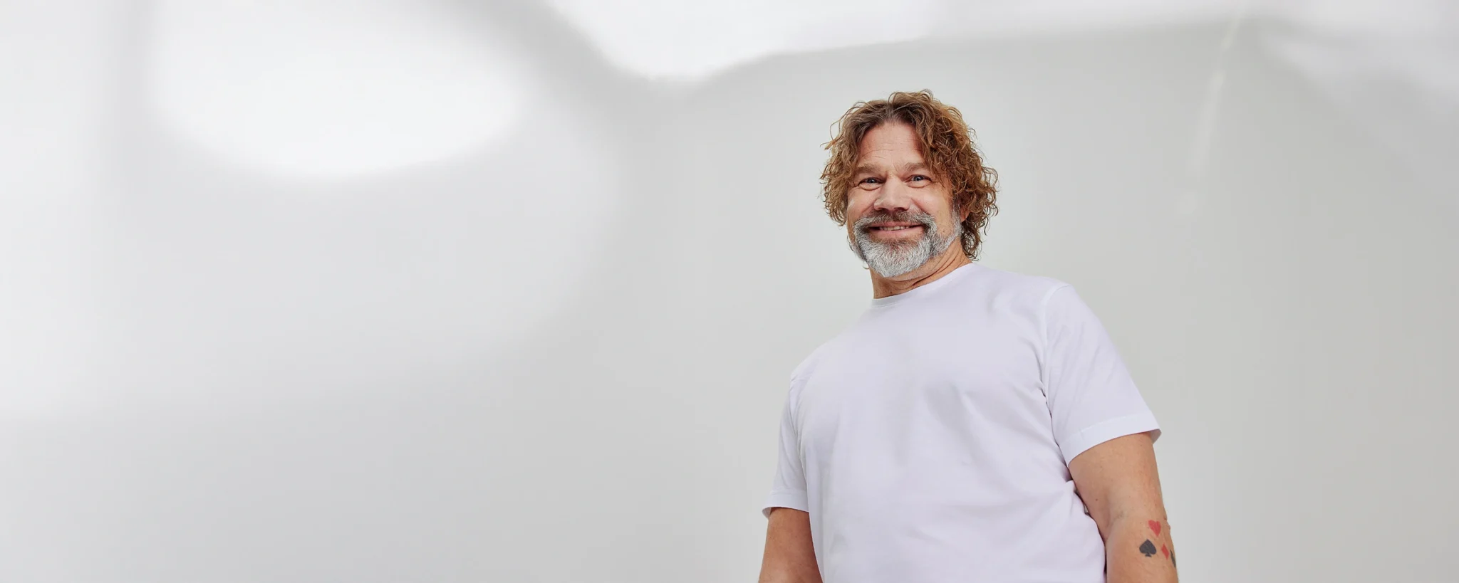 Dekorativ bild som föreställer en man i vit t-shirt med ett leende